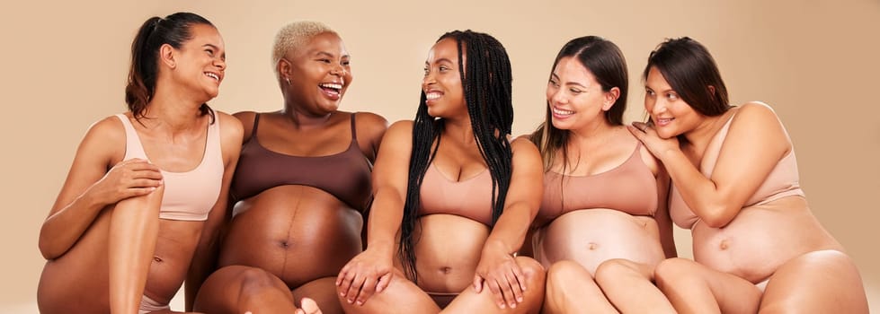 Laughing, bonding and pregnant women sitting on floor in community, diversity support or body wellness. Smile, happy and pregnancy friends in underwear with funny, comedy or comic joke for healthcare.