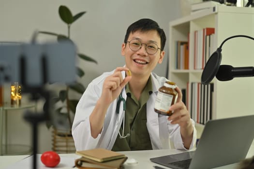 Doctor using microphone and laptop to recording audio about medication advise. Healthcare, medicine and blogging concept.