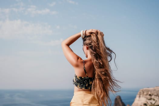 Woman travel sea. Happy tourist taking picture outdoors for memories. Woman traveler looks at the edge of the cliff on the sea bay of mountains, sharing travel adventure journey.