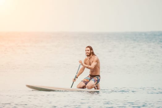 Sea woman and man on sup. Silhouette of happy young woman and man, surfing on SUP board, confident paddling through water surface. Idyllic sunset. Active lifestyle at sea or river