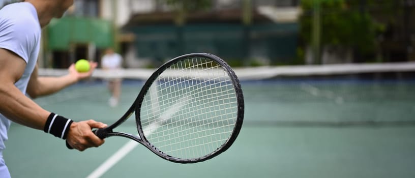 Cropped image of male tennis player with racket serving ball during match. Banner, copy space.