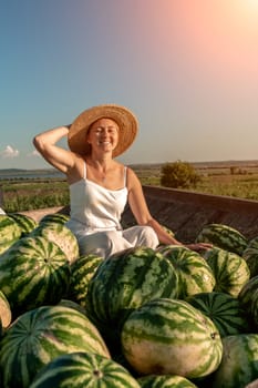 watermelon woman. He sits in a hat on a mountain of watermelons. Trailer with watermelons in the market