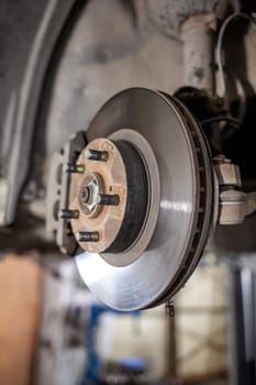 Disc brake of the vehicle for repair, in process of new tire replacement. Car brake repairing in garage.Suspension of car for maintenance brakes and shock absorber systems. Replacement of brake pads.