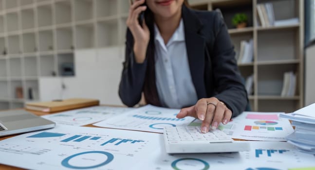 Close-up of businesswoman hands using a calculator to check company finances and earnings and budget. Business woman calculating monthly expenses, managing budget, papers.