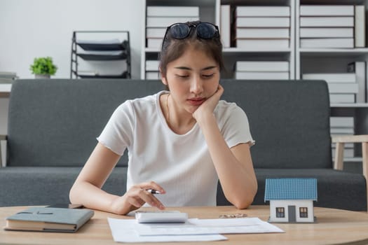 Young woman sit at desk at home manage household finances paying bills calculating on machine calculator. female care of budget use smartphone for payment. Finance concept.