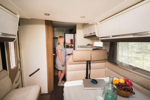 A woman opened a refrigerator in a mobile home.