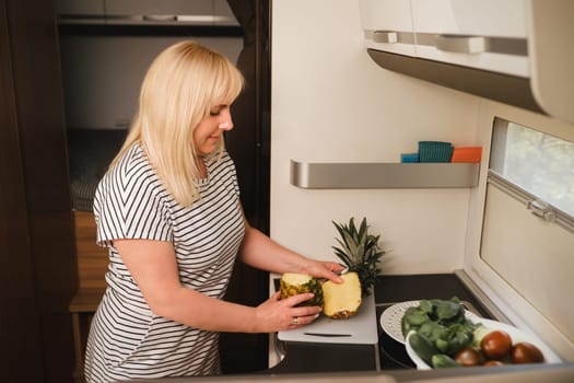 a woman cooking food in the kitchen inside a motorhome, the interior of a motorhome.