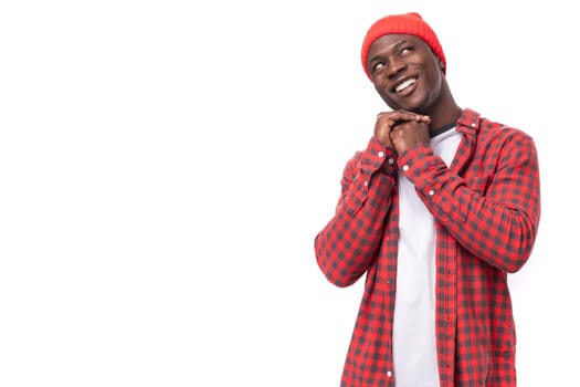 handsome young ethnic african guy in red plaid shirt reports dreaming over isolated white background.