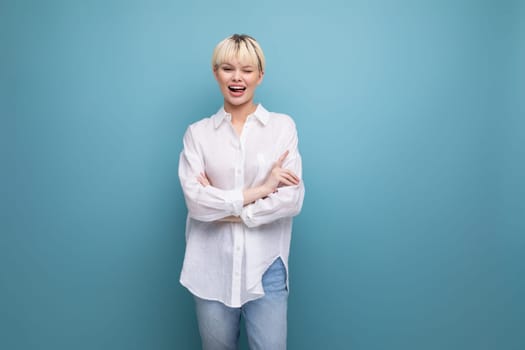 well-groomed cute blond fashionable woman with short haircut dressed in white shirt isolated on blue background with copy space.