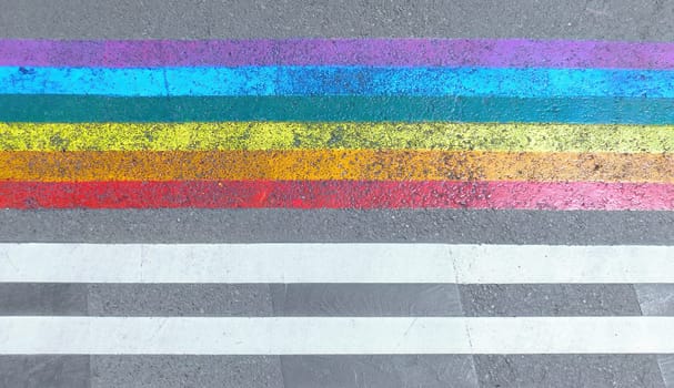 Marked crosswalk with lbgtq pride flag rainbow stripes. Colored chalk