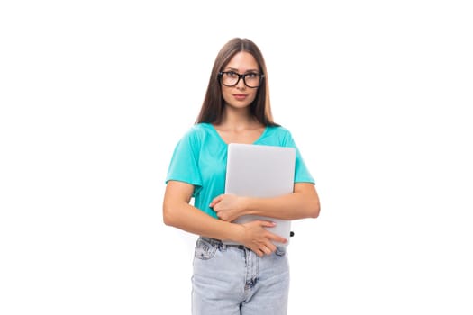 young brunette european lady with straight hair wearing glasses dressed in casual clothes holding a laptop for work.