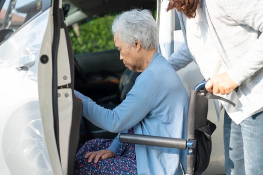 Caregiver help and support asian elderly woman sitting on wheelchair prepare get to her car to travel in holiday.