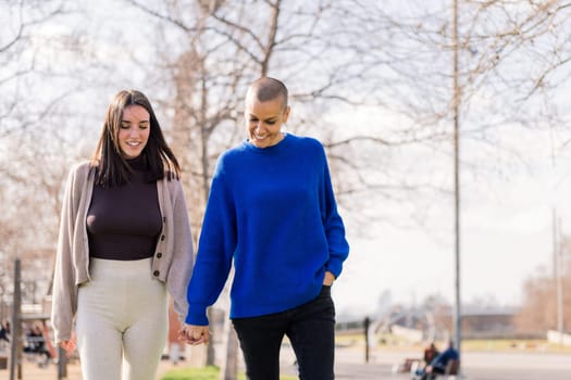 lesbian couple of two young women smiling happy taking a romantic walk in a city park, concept of freedom and love between people of the same sex