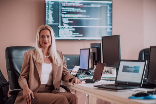 A businesswoman sitting in a programmer's office surrounded by computers, showing her expertise and dedication to technology