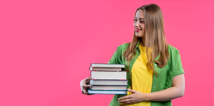 Adult happy student woman with stack of books from library on pink background. Happy girl smiles, she is happy to graduate. Copy space High quality