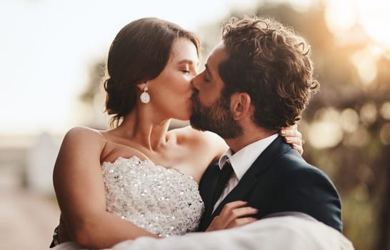 Love, wedding and kiss with a couple outdoor on their marriage day together for romance or tradition. Event, celebration or married with a birde and groom kissing outside after their ceremony.