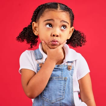 Kid, ideas or thinking face by isolated red background in games innovation, question or planning vision. Little girl, expression or curious finger on chin, children fashion clothes or curly hairstyle.