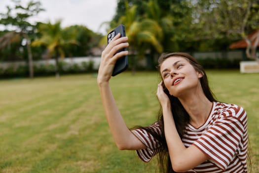 woman blogger shirt application palm phone tree t-shirt person talking talk lifestyle smiling park summer happy mobile cellphone call nature grass cell