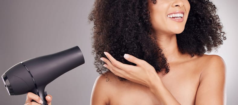 Hair care, beauty and black woman with hairdryer in studio isolated on gray background. Curly haircare, aesthetic or happy female model with machine to dry hairstyle after salon treatment for growth
