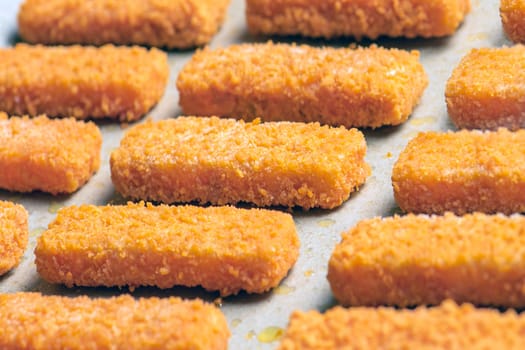 A lot of fish sticks ready for frying on special paper. Cooking concept for frying fish fingers in the oven. Side view. Close-up. High quality photo