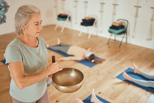 Meditation, class and woman with Tibetan singing bowl for calm, peace and zen in gym studio. Spiritual healing, mindfulness and senior fitness coach in yoga, exercise and pilates lesson for wellness.