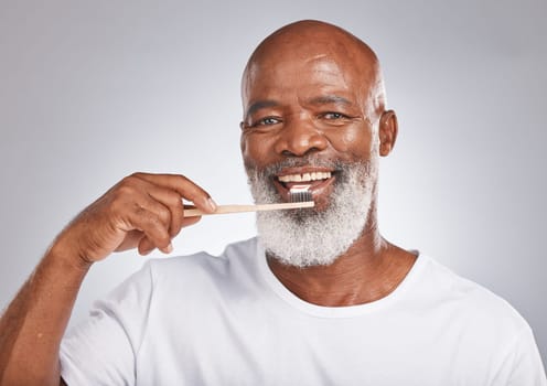 Brushing teeth, studio portrait and black man with toothbrush for mature dental wellness, healthy lifestyle or cleaning aesthetic in Nigeria. Happy face, male model and oral mouth care of fresh smile.