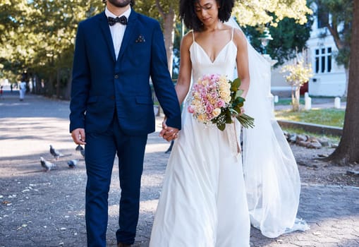 Love, wedding and couple with flowers holding hands outdoors at park together. Marriage, diversity or affection, care or romance of man, woman or bride and groom walking with bouquet of roses