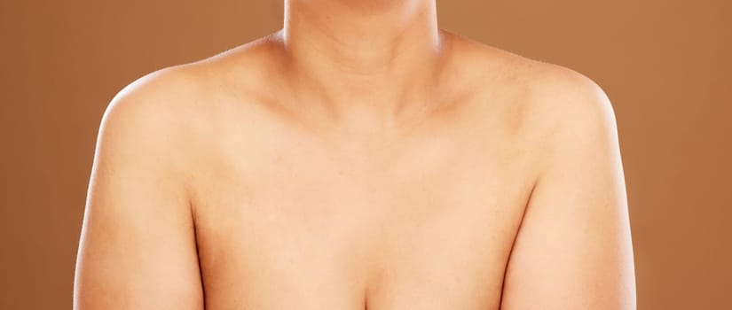 Woman, chest and skincare on a brown studio background for health, wellness and breast cancer awareness. Human body, skin and bust of a female model posing naked for healthcare and self care.