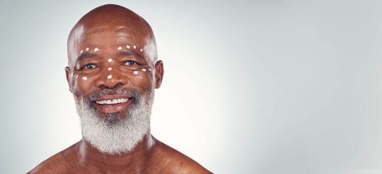 Skincare, portrait and senior man relax in studio with face cream, sunscreen and product on grey background. Facial, wrinkles and elderly model happy with skin, treatment and luxury cosmetics.