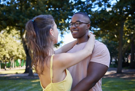 Summer, love and diversity with a couple bonding outdoor together in a park or natural garden. Nature, interracial and romance with a man and woman hugging while on a date outside in the countryside.