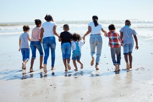 Big family, beach walk and water for vacation, sunshine and bonding with interracial diversity by waves. Happy family, mother and holding hands for solidarity, care and love on holiday by sea.