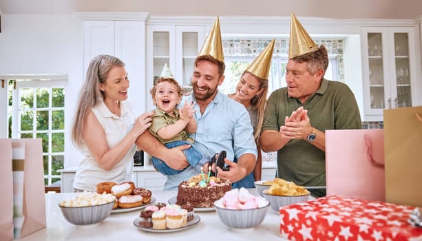 Baby, birthday party and family celebration at a kid event with mother, father and friends. Young child and parents celebrate event with food clapping for a happy boy in a family home kitchen.