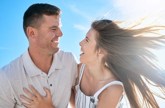 Couple, love and hug together in summer for travel adventure vacation outdoors. Excited woman, happy man and funny comedy conversation, romance bonding and quality time or support in sunshine.