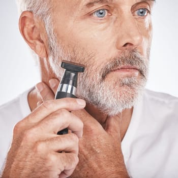 Senior man, shaving and electric razor for hair care, beauty and cosmetics on studio background. Mature male, elderly guy and shave for facial routine, beard trim and wellness for health and skincare.