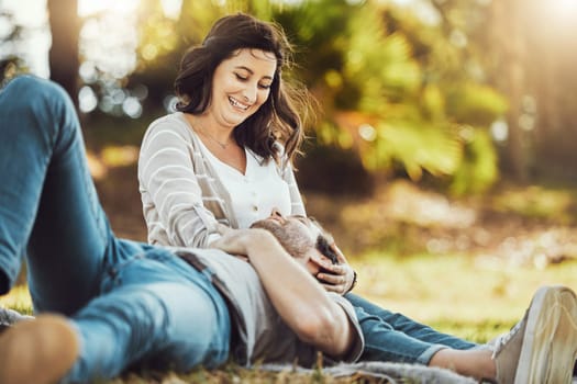Love, relax and couple at park, laughing at funny joke or comic comedy and having fun together outdoors. Valentines day, romance cuddle and care of man lying on lap of happy woman on romantic date