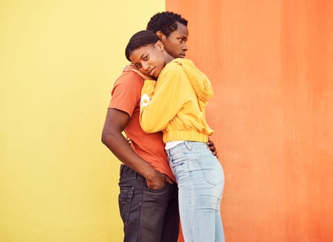 Love, hug and comfort with a black couple together outside on a color wall background for romance or dating. Hugging, date and consoling with a man and woman holding each other in support or care.