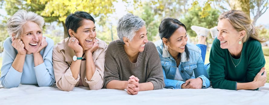 Senior women, friends and relax on picnic in park for bonding, wellness and rest on blanket. Happiness, comic and group of elderly people in retirement talking, laughing and enjoying time in nature