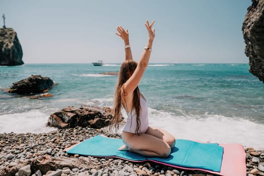 Young woman with black hair, fitness instructor in pink sports leggings and tops, doing pilates on yoga mat with magic pilates ring by the sea on the beach. Female fitness daily yoga concept