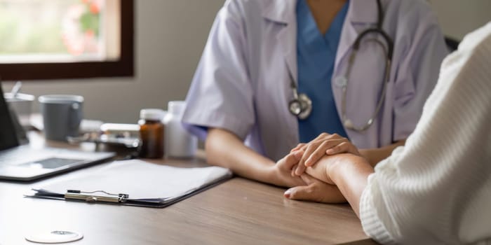 Hand of doctor reassuring her senior female patient. Medical ethics and trust concept.