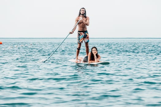 Silhouette of woman standing, surfing on SUP board, confident paddling through water surface. Idyllic sunset or sunrise. Sports active lifestyle at sea or river.