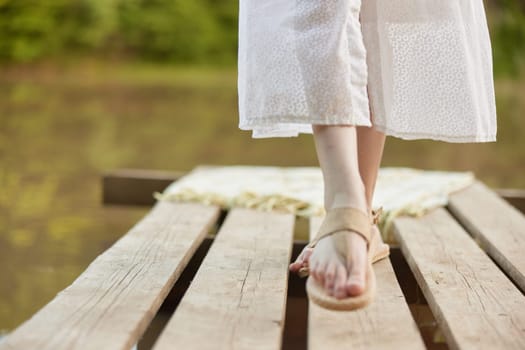 girl's legs in summer sandals on the pier in summer. High quality photo