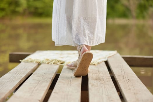 girl's legs in summer sandals on the pier in summer. High quality photo