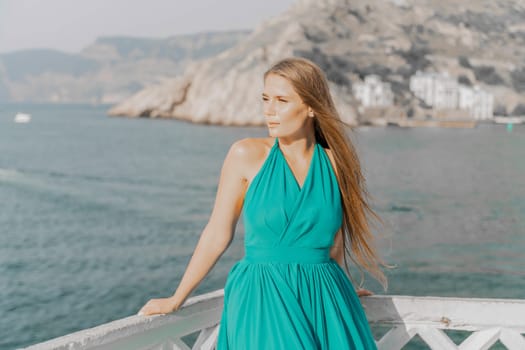 Woman sea trevel green dress. Side view a happy woman with long hair in a long mint dress posing on a beach with calm sea bokeh lights on sunny day. Girl on the nature on blue sky background