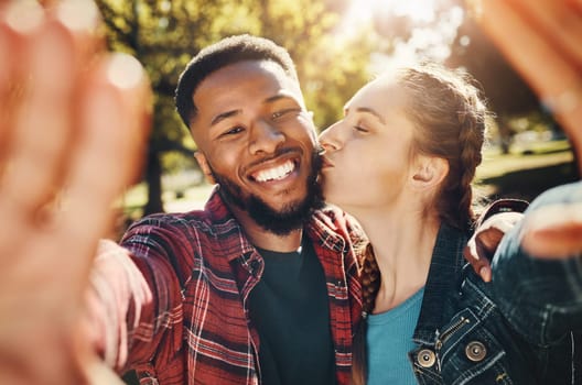 Interracial couple, selfie kiss and portrait in nature, having fun and bonding together outdoors. Smile, love romance and black man and woman kissing to take photo for happy memory or social media