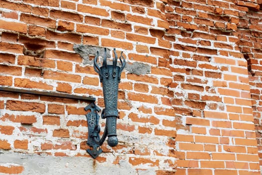Metal lantern in the form of an ancient torch on the fortress wall