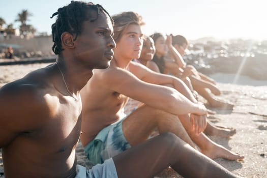 Black man, bonding and sitting on beach sand with friends in summer holiday, vacation break or community travel. Relax, diversity and people in swimsuit by sea for nature freedom or social gathering.