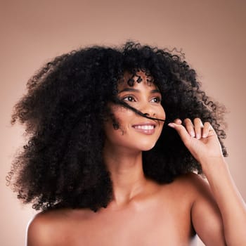 Hair in hands, beauty and black woman with smile on brown background for wellness, shine and natural glow. Salon, luxury treatment and happy girl face with curly hairstyle, texture and afro growth.