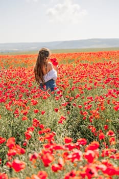 Woman poppies field. Back view of a happy woman with long hair in a poppy field and enjoying the beauty of nature in a warm summer day