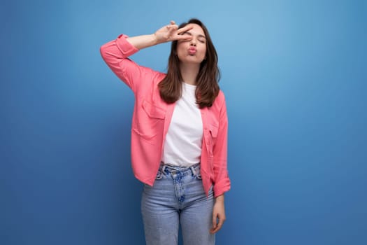 young woman in a pink shirt and jeans with a smile on a studio isolated background.