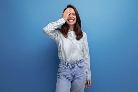 european young brunette female adult in a striped shirt and jeans with hair below her shoulders in a studio background.